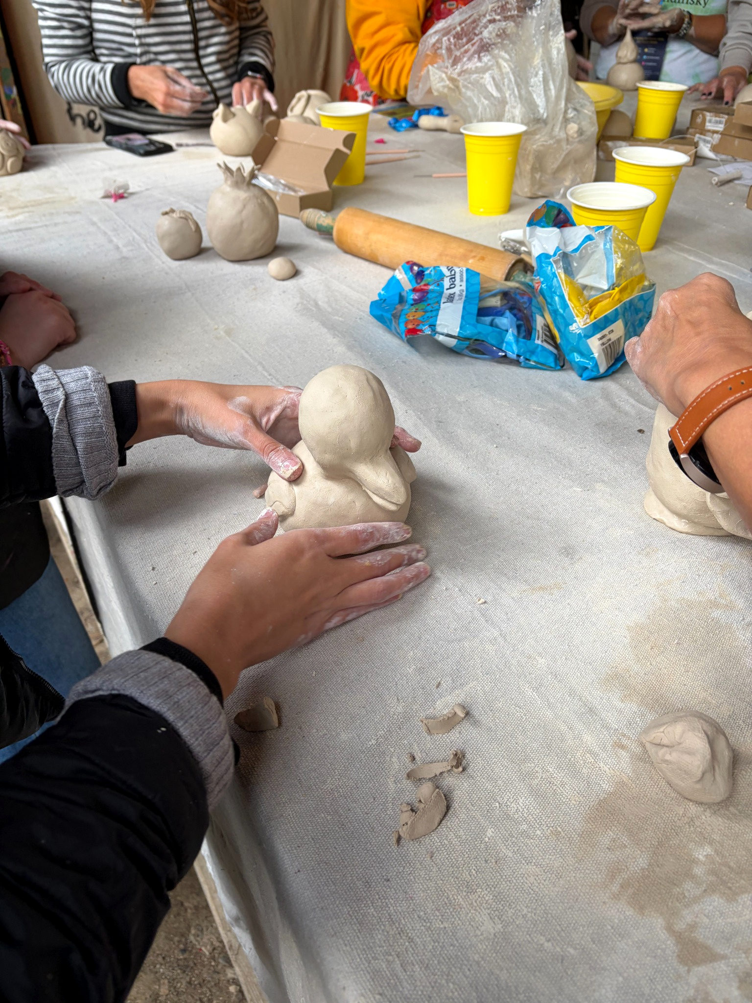 Workshop participant holding a developing clay animal form while refining its features