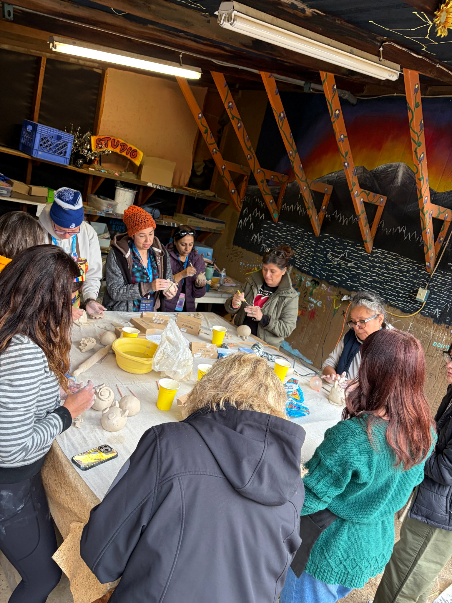 Art educators gathered around a studio table while sculpting clay during the AAEA workshop