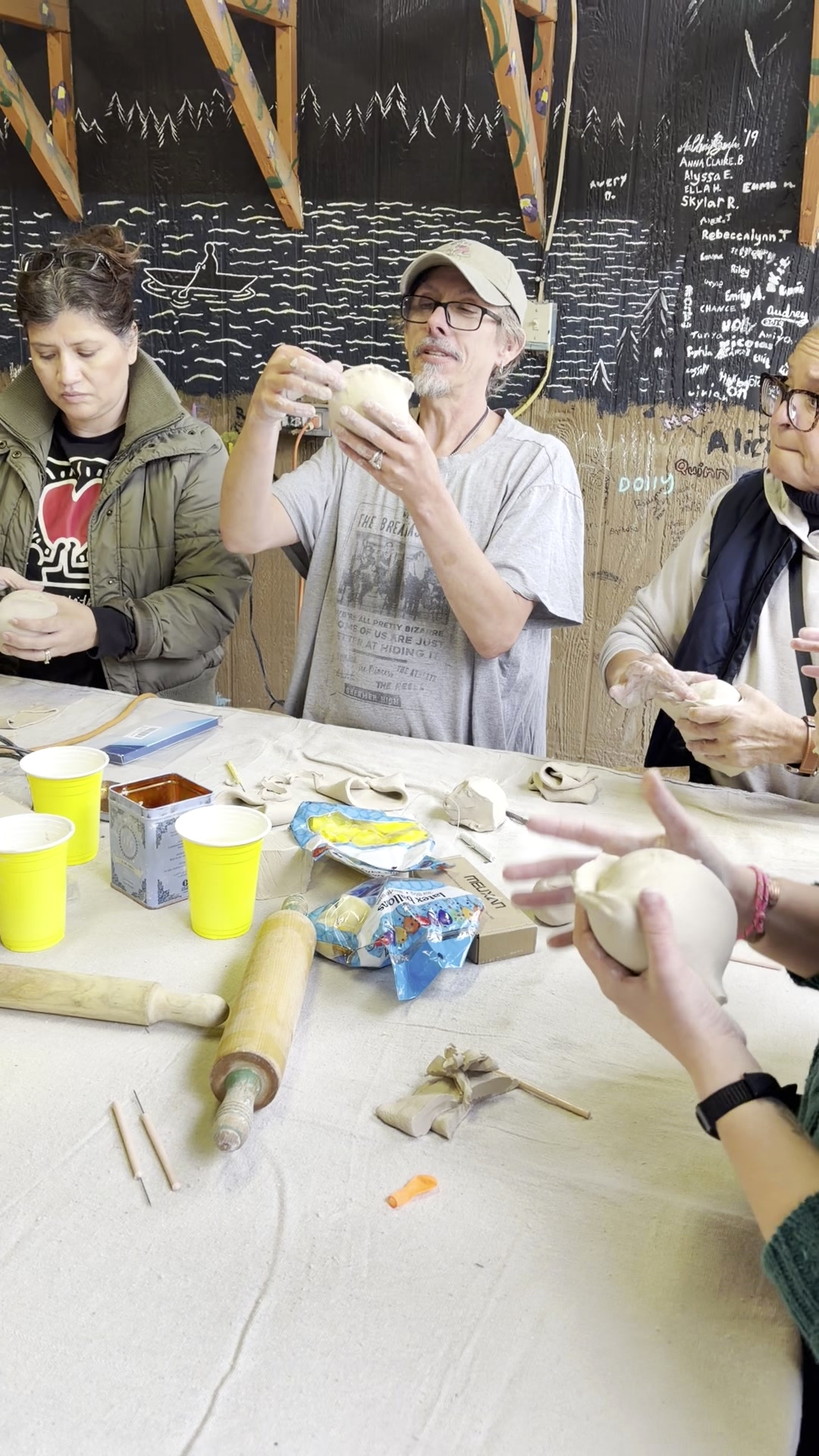 Spencer Tracy Brown holding up a rounded clay form to demonstrate a construction technique to fellow educators