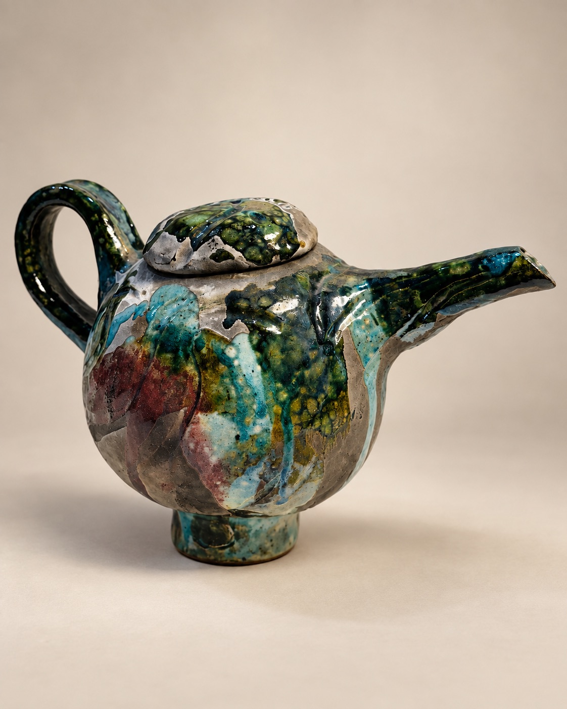 Handcrafted ceramic teapot with layered teal, forest green, turquoise, burgundy, and earthy glaze