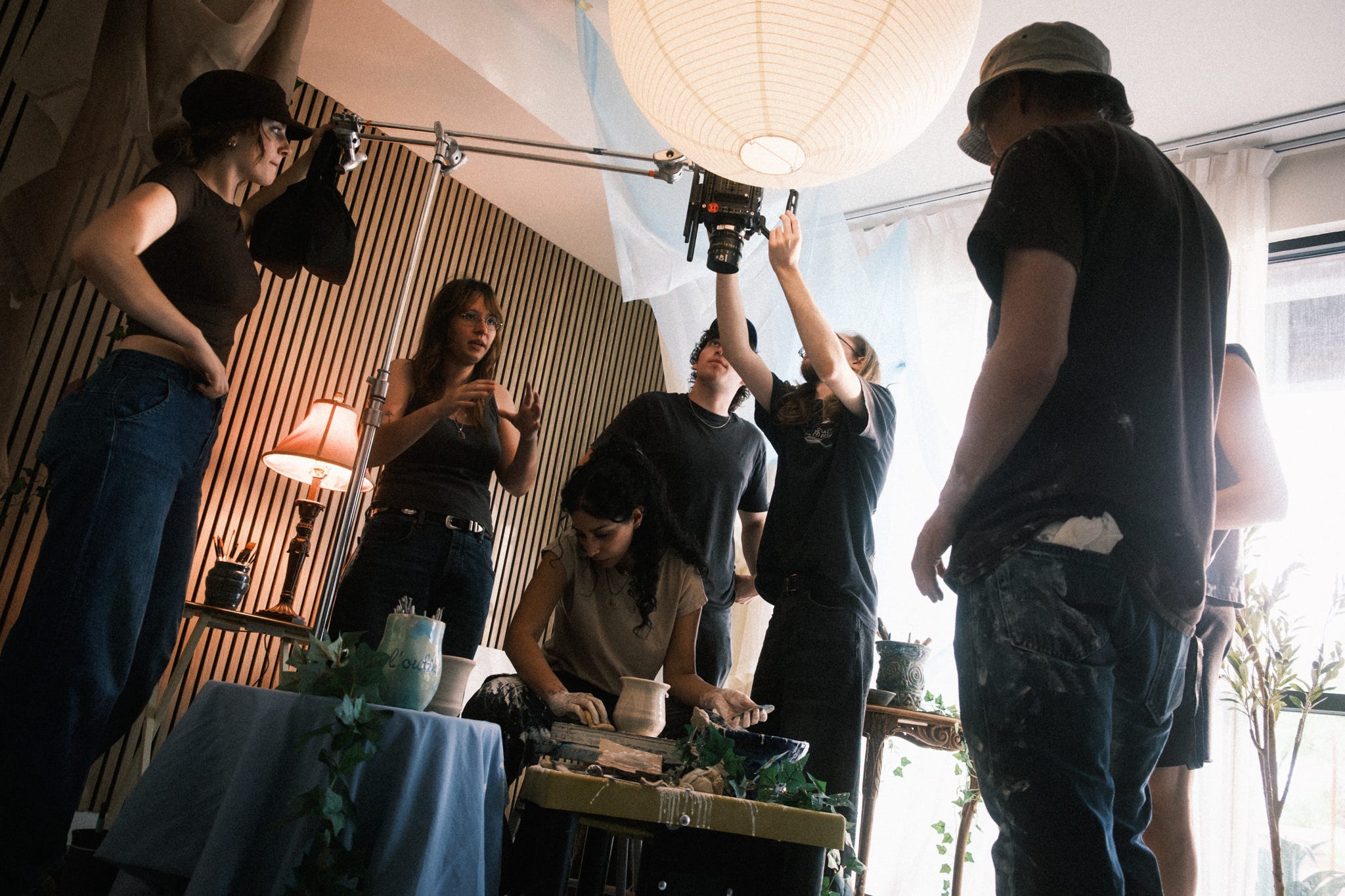 Made Anew cast and crew gathered around the ceramics set while adjusting camera equipment
