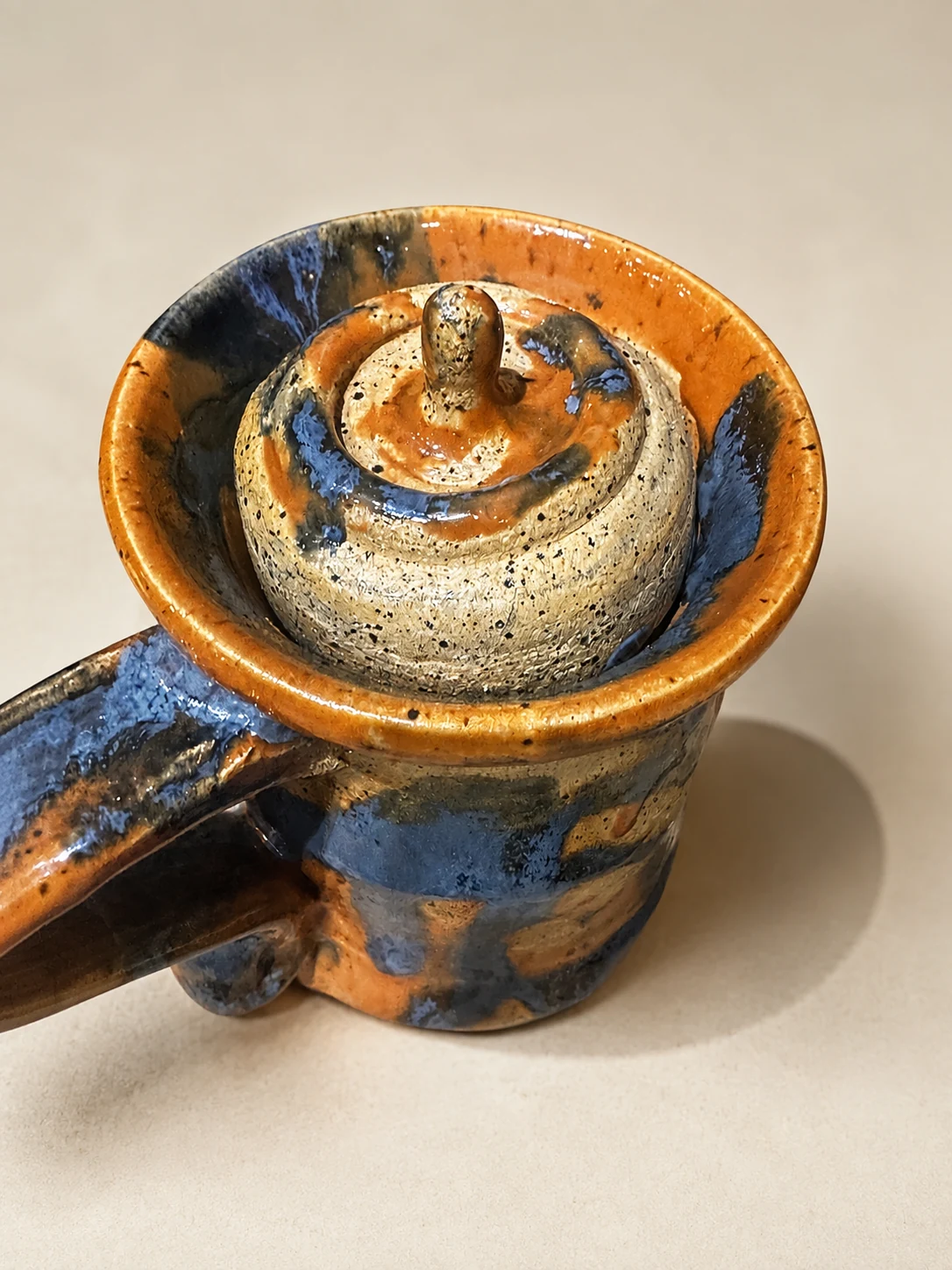 Handmade lidded ceramic vessel with mottled blue and warm orange glaze